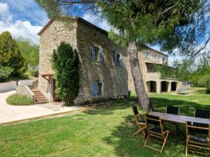 un edificio con un tavolo e un albero di fronte ad esso di Mas de Rofa proche Pôle mécanique Alès a Saint-Martin-de-Valgalgues