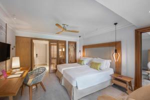 a bedroom with a white bed and a desk at Sugar Beach Mauritius in Flic-en-Flac