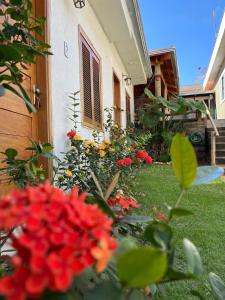 um jardim com flores vermelhas em frente a uma casa em Pousada Sempre Viva em São João Batista do Glória