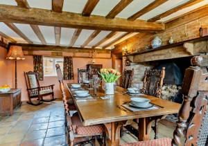 uma sala de jantar com uma mesa de madeira e uma lareira em Corner Farm Cottage em Rumburgh