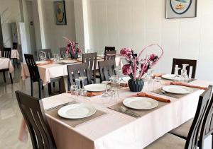 ein Esszimmer mit einem Tisch mit weißen Tellern und Blumen in der Unterkunft HOTEL CONTINENTAL in Abidjan