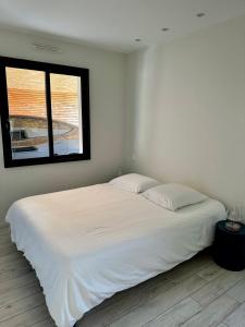 Cama blanca en habitación con ventana en Maison vacances Bassin d'Arcachon en Gujan-Mestras