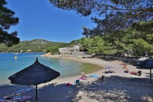 a beach with people laying on the sand and an umbrella at Luxury mobile home HIMALAJA, Oaza mira, Drage in Drage