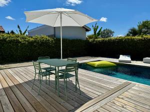 een tafel en stoelen met een parasol naast een zwembad bij Maison vacances Bassin d'Arcachon in Gujan-Mestras