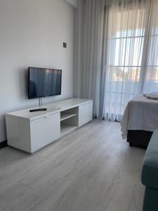a living room with a television on a white cabinet at Cicek Apart Hotel in Cesme