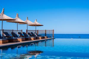 a pool with chairs and umbrellas and the ocean at Sea Valley Lodge in Faralya