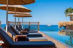 a row of chairs and umbrellas next to a swimming pool at Sea Valley Lodge in Faralya