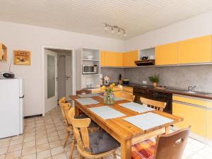 eine Küche mit einem Holztisch und eine Küche mit gelben Schränken in der Unterkunft Apartment Waldblick-2 by Interhome in Armstorf