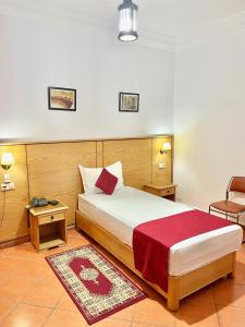 ein Schlafzimmer mit einem Bett, einem Stuhl und einem Tisch in der Unterkunft Sary's Hotel in Mʼdik