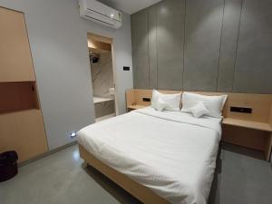 a bedroom with a bed with white sheets and pillows at Hotel Golden Suites - Near Nesco in Mumbai +15 photos