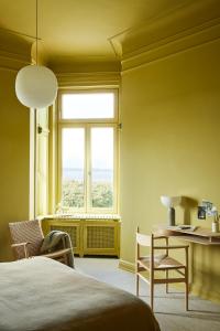a bedroom with a bed and a desk and a window at stilwerk Strandhotel Blankenese in Hamburg