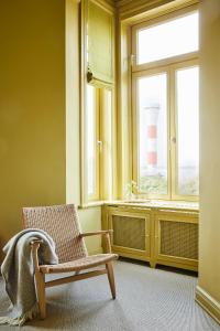 ein Badezimmer mit einem Stuhl und ein Fenster mit einem Leuchtturm in der Unterkunft stilwerk Strandhotel Blankenese in Hamburg