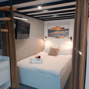 ein Schlafzimmer mit einem Bett und einem Fernseher an der Wand in der Unterkunft Apartament typu studio Morski Sen-centrum in Mielno