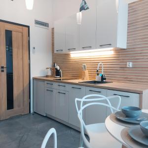 een keuken met witte kasten, een wastafel en een tafel bij Apartament typu studio Morski Sen-centrum in Mielno