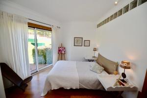 a white bedroom with a bed and a window at Paddle - Sea view apartment with 3 pools, tennis & squash court in São Martinho do Porto +45 photos