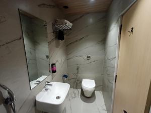 a white bathroom with a sink and a toilet at Hotel Golden Suites - Near Nesco in Mumbai