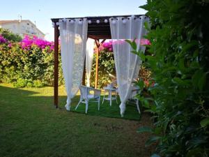 een prieel met een tafel en stoelen eronder bij Sardinia Guest House in Olmedo