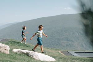 twee jonge kinderen die op een grasheuvel lopen bij Familienhotel Familiamus in Maranza