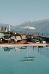 una piscina con sillas y sombrilla en Familienhotel Familiamus en Maranza