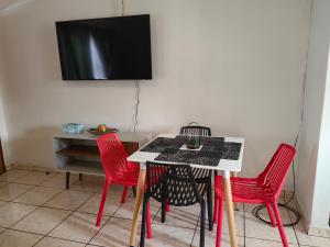 mesa con 4 sillas rojas y TV en la pared en Apartment on MR103 en Mbabane
