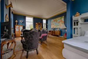 a bedroom with blue walls and a bed and chairs at Villa Dalenstein in Velp