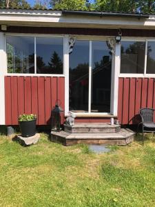 ein rotweißes Haus mit einer Veranda und einem Stuhl in der Unterkunft Gävle Järvsta nära Furuvik och centrala Gävle in Gävle