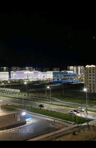 a night view of a highway with buildings and street lights at Comfort Turkestan in Türkistan