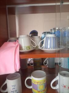 un estante con un montón de tazas y tazas en Pearl furnished residence, en Buloba