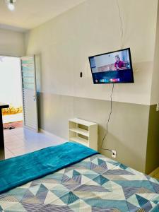 a bedroom with a bed with a flat screen tv on the wall at Casa da Vó Maria! Studio 08 in Goiânia