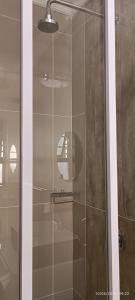 a shower with a glass door in a bathroom at 40 on King BnB in East London