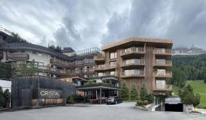 un grande edificio con un'auto parcheggiata di fronte di Hotel Cristal a Obereggen