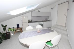 cocina blanca con mesa blanca y sillas en Rooms and Apartment Luana, en Rovinj