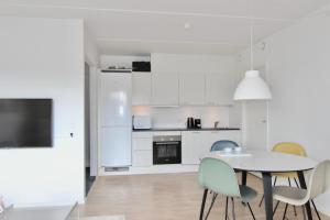 uma cozinha branca com mesa e cadeiras em Cool 1-bed w. private terrace em Odense