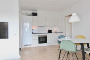 uma cozinha com armários brancos e uma mesa e cadeiras em Cool 1-bed w. private terrace em Odense