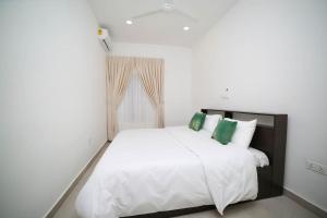 1 dormitorio blanco con 1 cama blanca grande con almohadas verdes en The Chelsea TownHouse C en Accra