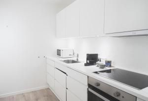 a white kitchen with two sinks and white cabinets at Fantastic apartment wprivate terrace in Aarhus