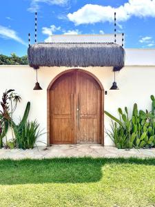 una casa con una porta in legno e un tetto di paglia di CASA CACTOS a São Miguel do Gostoso