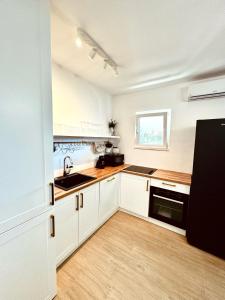 una cocina con armarios blancos y fregadero en Apartments Lorena, en Primošten