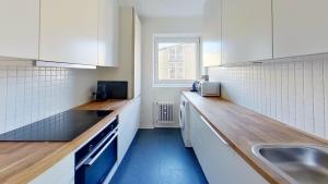 una cucina con armadi bianchi, lavandino e finestra di Beautiful 2-bed in Frederiksberg C a Copenaghen