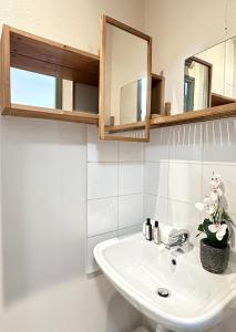 een badkamer met een witte wastafel en spiegels bij 5496 - Studio Montparnasse Olympic Games 2024 in Parijs