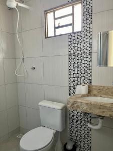 a bathroom with a toilet and a sink and a window at Casa da Vó Maria! Studio 08 in Goiânia