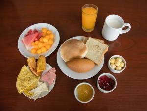 a table with plates of breakfast food and a cup of orange juice at Royal Inn Cusco Hotel in Cusco