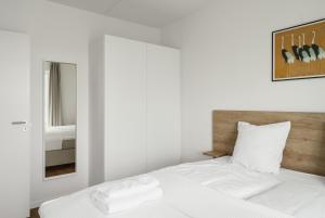 Top-class 1-bedroom apartment in Odense في أودنسه: غرفة نوم بسرير وملاءات بيضاء ومرآة