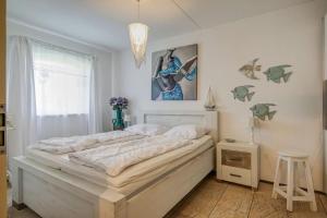 a bedroom with a large white bed and a window at Appartement Regina - Residence Juliana Julianadorp aan Zee in Julianadorp