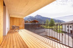 a wooden balcony with a desk and a view of mountains at Kitzbühel Suites by ALPS RESORTS in Oberndorf in Tirol