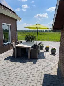 Schalkhaar的住宿－De Steerne, mooie plek aan het Overijssels kanaal.，庭院配有桌椅和遮阳伞。
