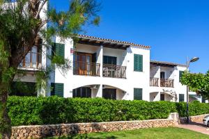 a large white building with green shutters at Apartamento Arenal de'n Castell in Arenal d'en Castell