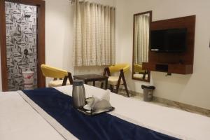 a hotel room with a bed with a table and a tv at Guru Kripa sadan in Vrindāvan