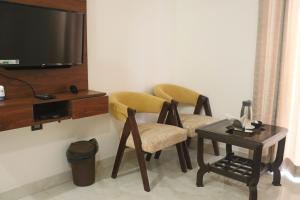 Cette chambre dispose de 2 chaises, d'une table et d'une télévision. dans l'établissement Guru Kripa sadan, à Vrindavan
