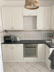 a kitchen with white cabinets and a stove and a microwave at Zazie Apartment with free parking in Budapest +7 photos
